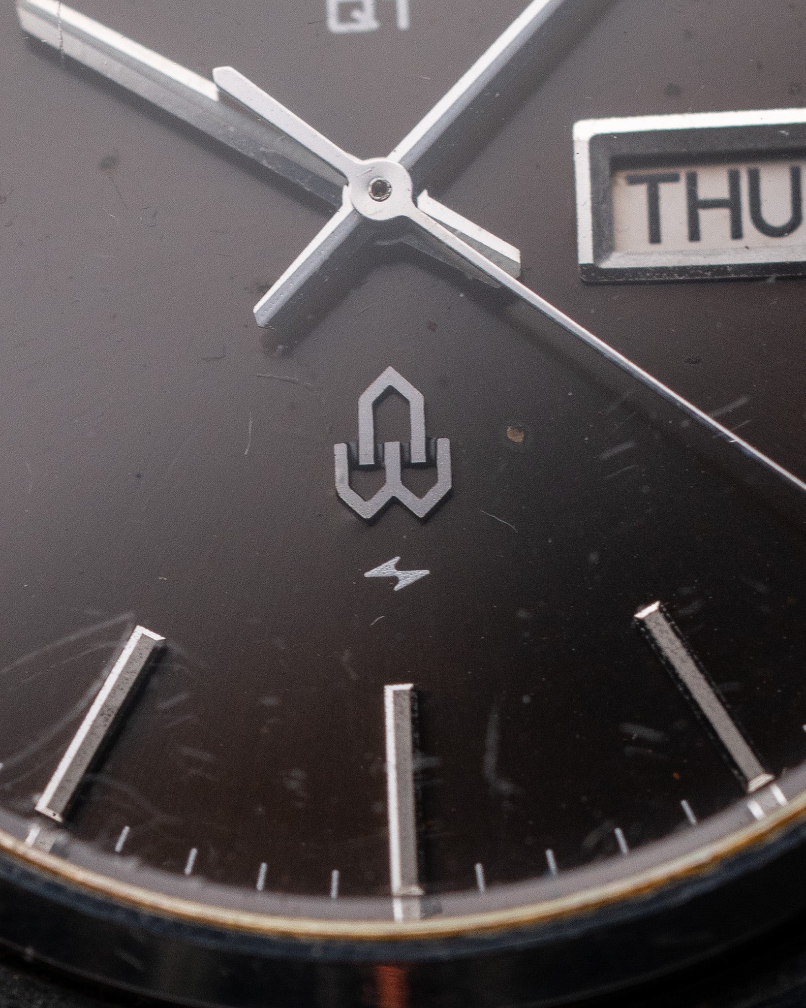 Close-up of a watch face with brand logo and day display